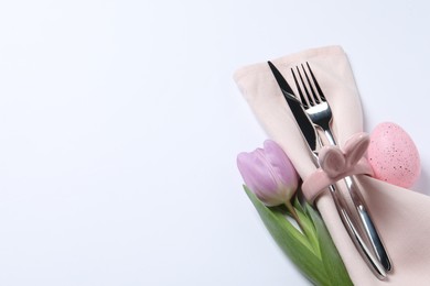 Cutlery set, Easter egg and tulip on white background, space for text. Festive table setting