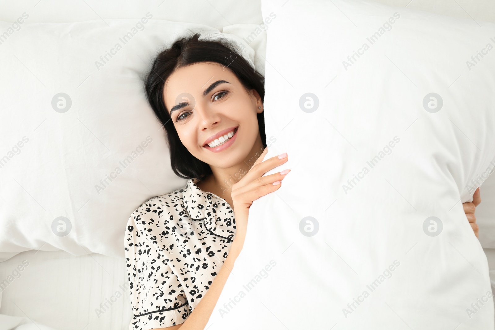 Photo of Young woman with pillow in bed, top view. Lazy morning