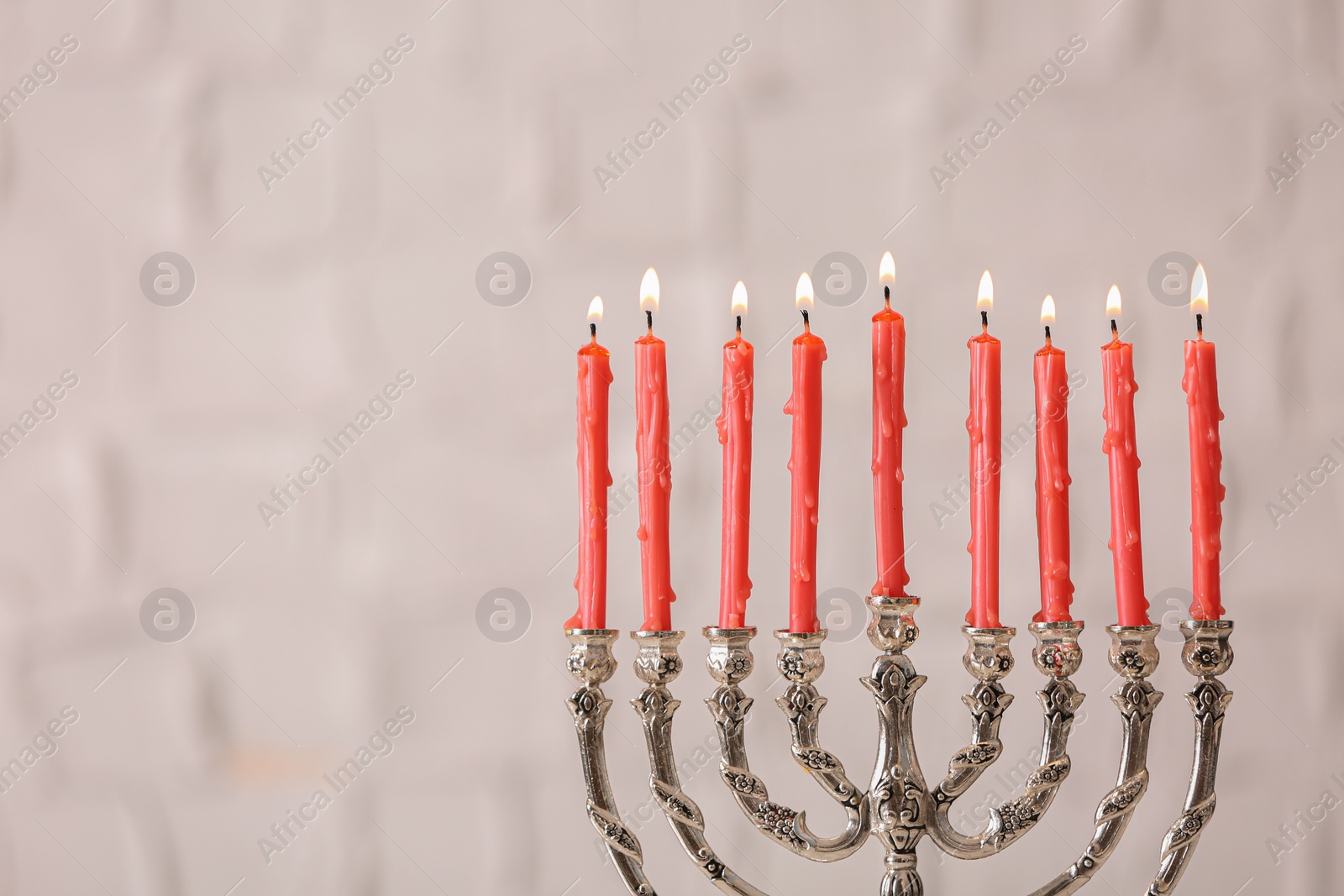 Photo of Silver menorah with burning candles on light background, space for text. Hanukkah celebration