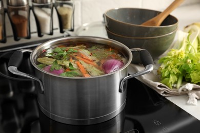 Pot of delicious vegetable bouillon on stove in kitchen