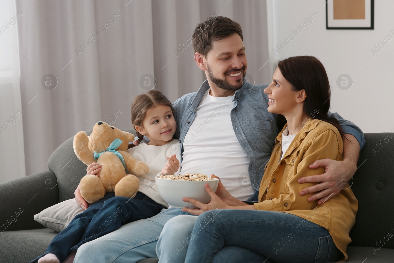 Photo of Happy family spending time together while watching TV at home