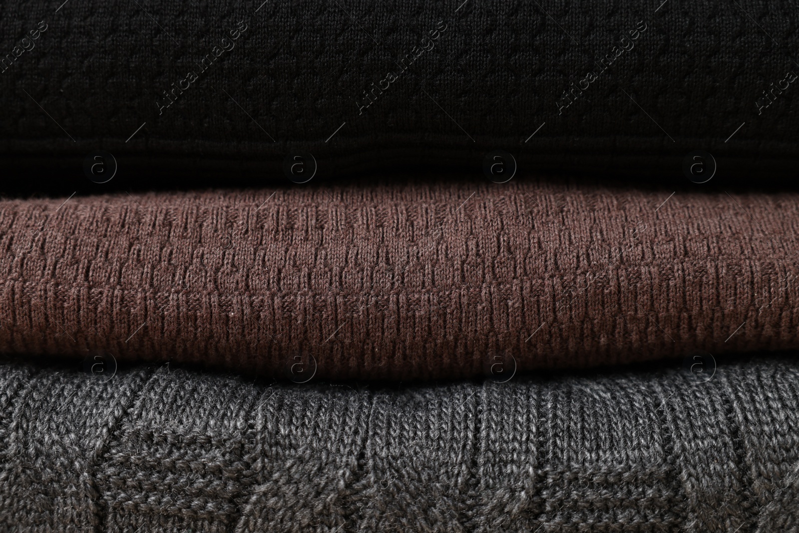 Photo of Stack of casual warm sweaters as background, closeup view