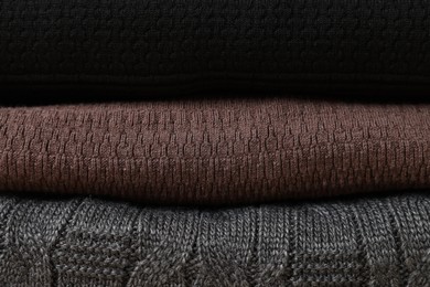 Stack of casual warm sweaters as background, closeup view