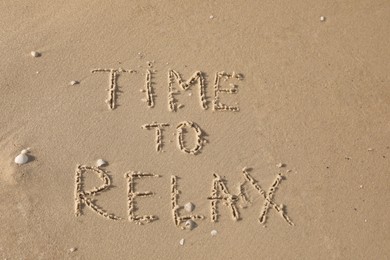 Photo of Phrase Time to Relax written on sand at beach, top view