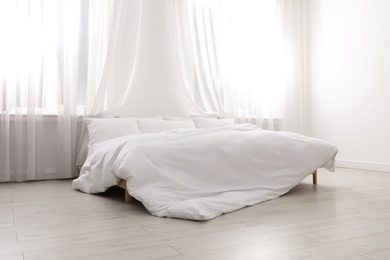 Photo of Comfortable bed in light room. Interior design