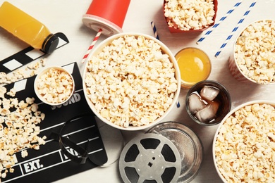 Photo of Flat lay composition with popcorn, cinema clapperboard and film reel on light background