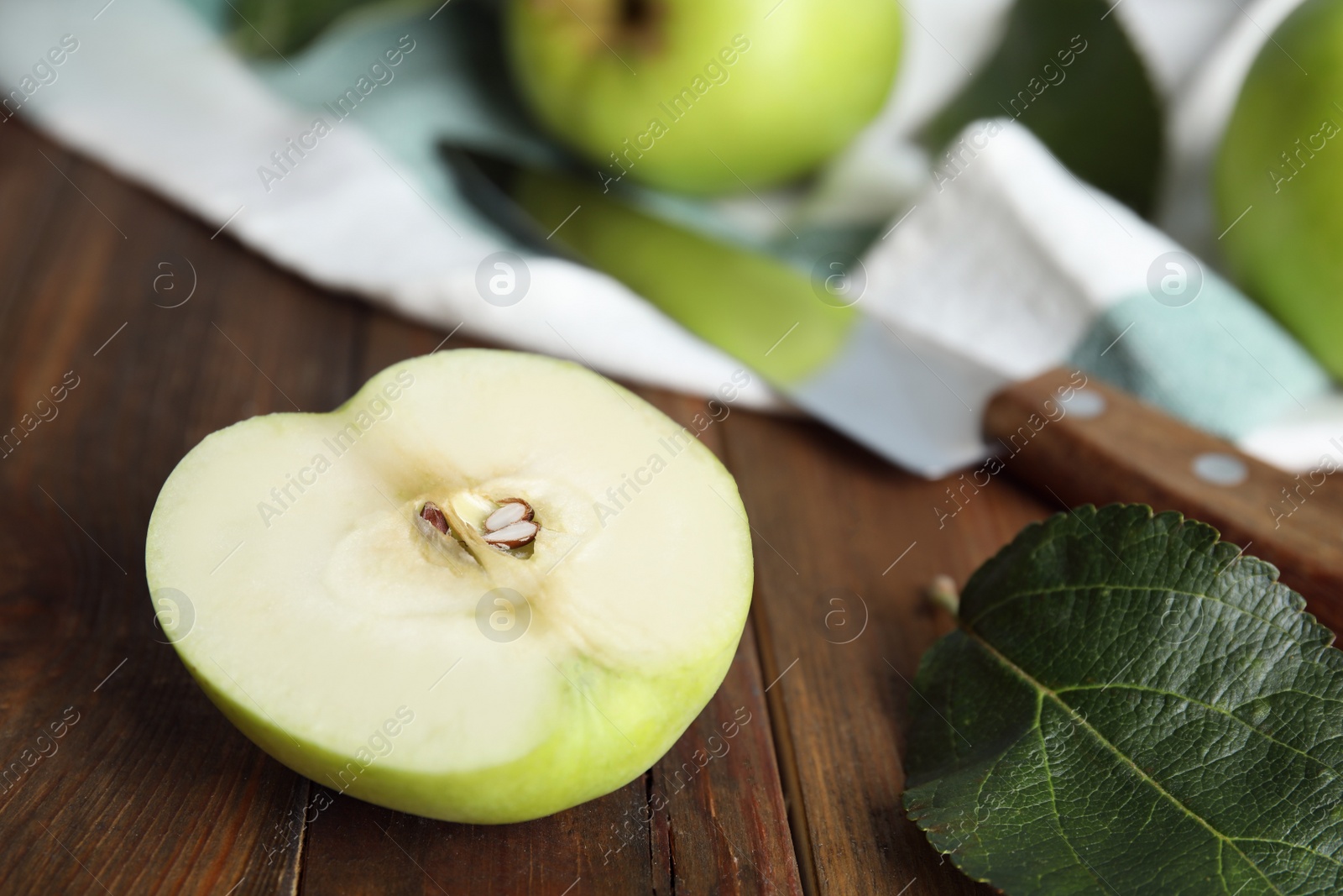 Photo of Half of fresh ripe green apple and leaf on wooden table