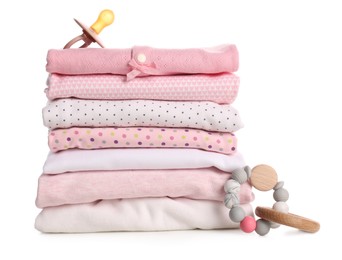 Photo of Stack of baby girl's clothes, pacifier and rattle on white background