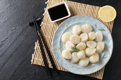 Raw scallops with lemon, rosemary and soy sauce on dark textured table, flat lay