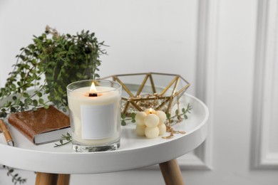 Photo of Burning candles, notebook and houseplant on white wooden table indoors