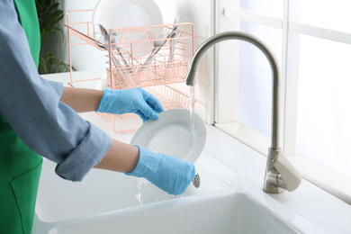 Woman washing plate in modern kitchen, closeup