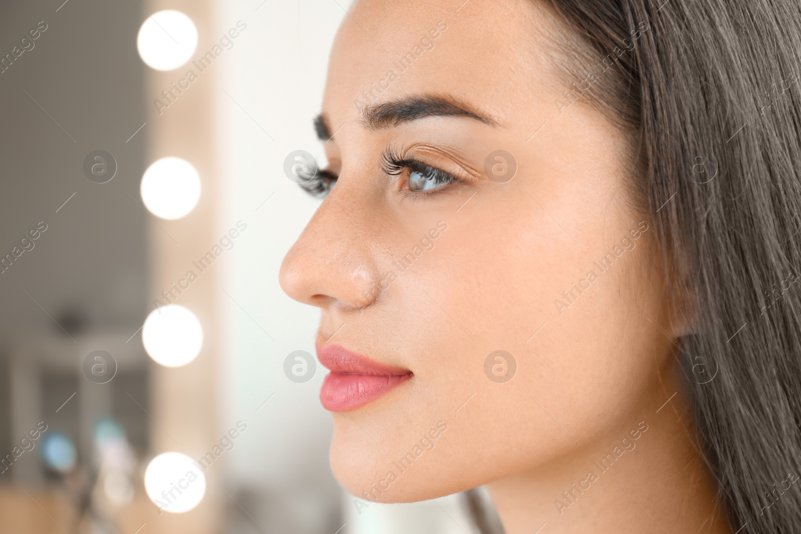 Photo of Attractive young woman with beautiful eyelashes on blurred background