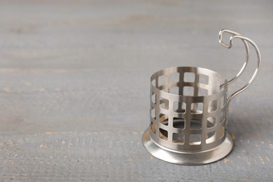 Photo of Traditional tea glass holder on grey wooden table, space for text