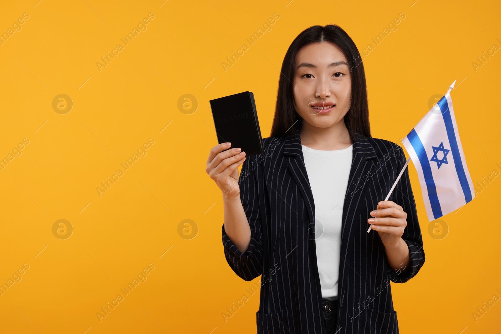 Photo of Immigration to Israel. Happy woman with passport and flag on orange background, space for text