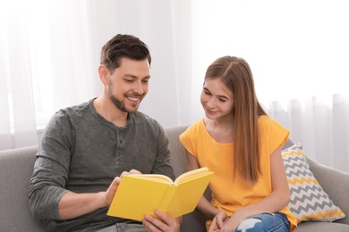 Father and his teenager daughter with book at home