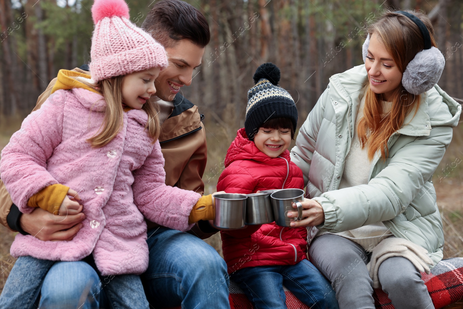 Photo of Happy family with cups of hot tea spending time together in forest