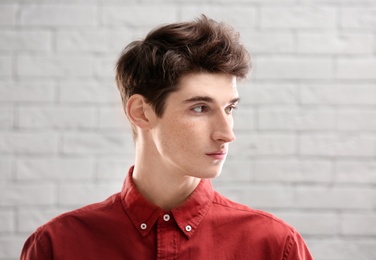 Photo of Portrait of young man with beautiful hair on brick wall background