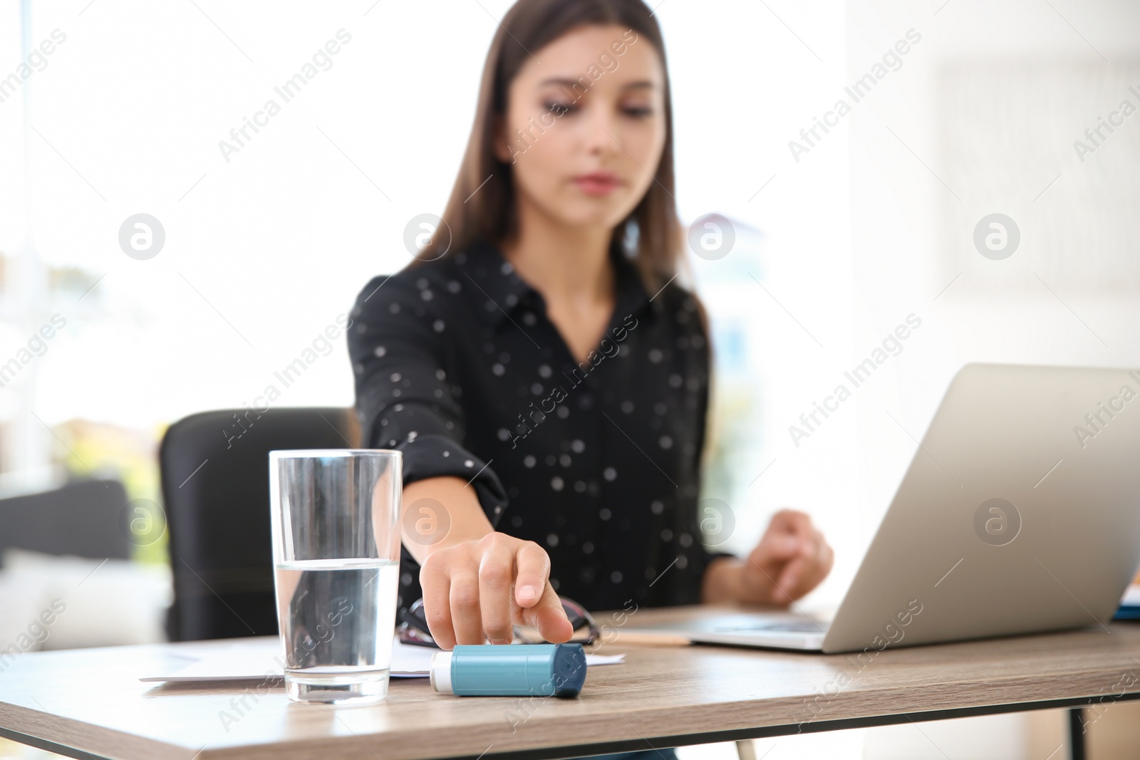 Photo of Woman with asthma inhaler at table in light room
