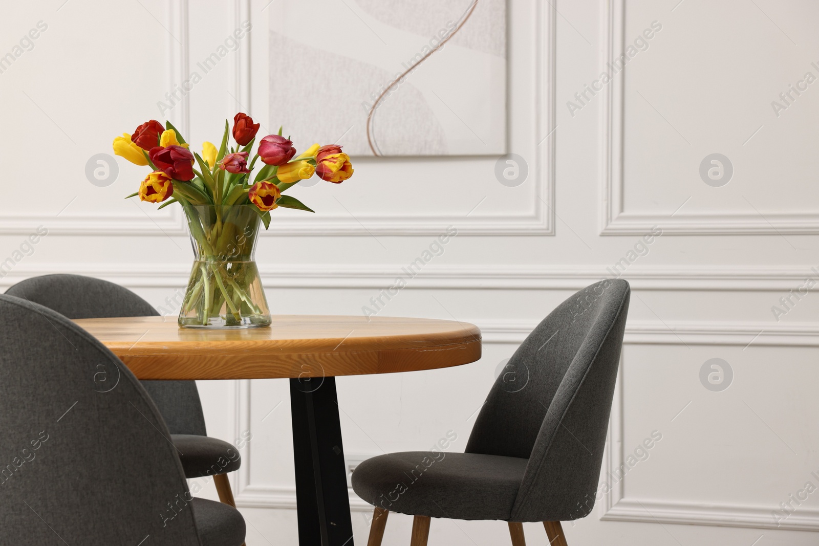 Photo of Vase with beautiful tulips on table in dining room