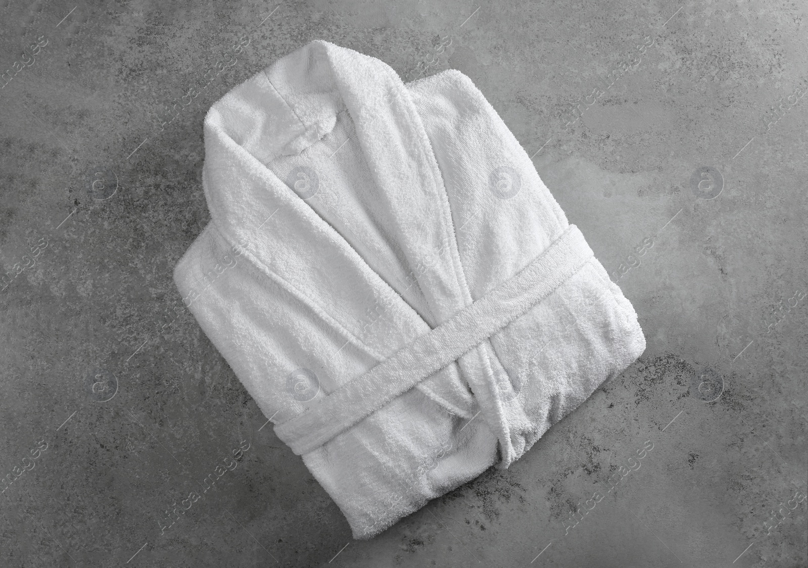 Photo of Clean folded bathrobe on grey stone background, top view