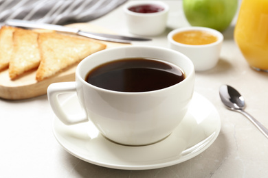 Photo of Fresh hot coffee on light grey marble table. Tasty breakfast