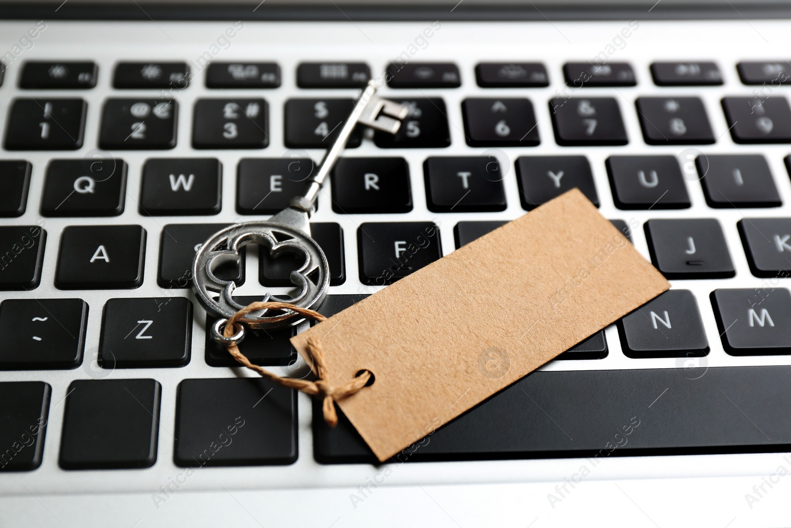 Photo of Key with blank tag on laptop keyboard, closeup. Keyword concept