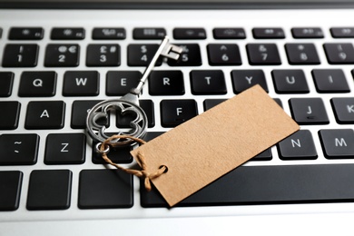 Photo of Key with blank tag on laptop keyboard, closeup. Keyword concept