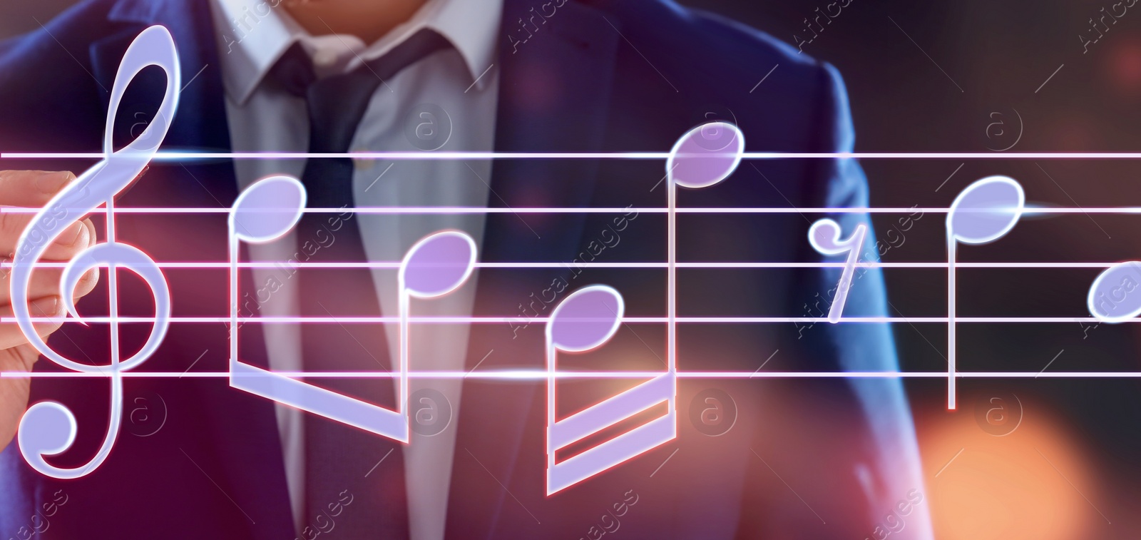 Image of Man with pen writing staff with music notes and symbols on color background, closeup. Banner design