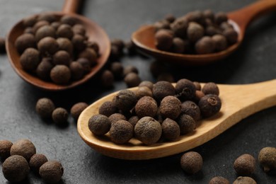 Photo of Dry allspice berries (Jamaica pepper) on black table, closeup