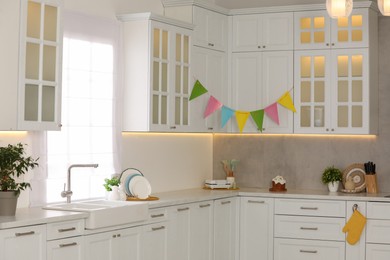 Photo of Stylish white kitchen with colorful decor. Interior design