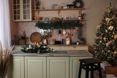 Stylish kitchen with festive decor and Christmas tree. Interior design