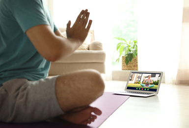 Image of Distance yoga course during coronavirus pandemic. Man having online practice with instructor via laptop at home, closeup