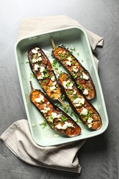 Baking dish with fried eggplant slices on grey background, top view