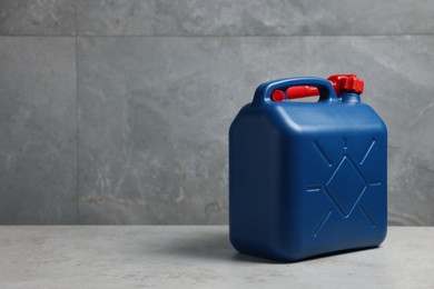 Photo of New blue plastic canister on floor near light grey wall, space for text