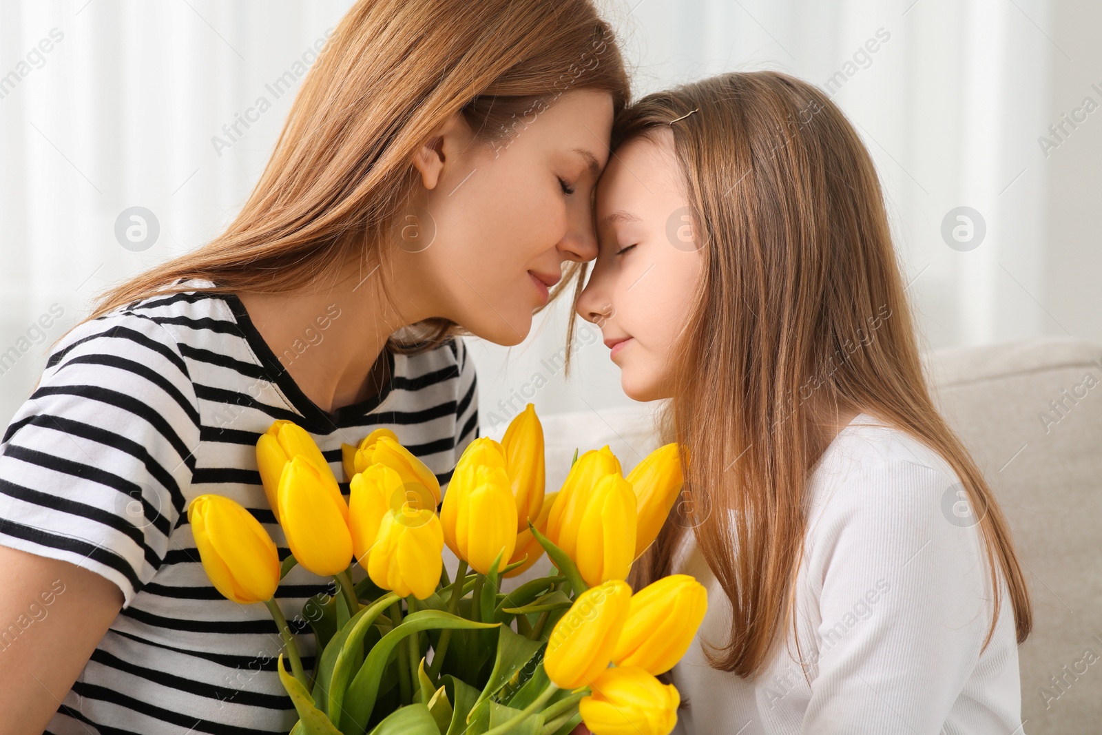 Photo of Mother and her cute daughter with bouquet of yellow tulips at home