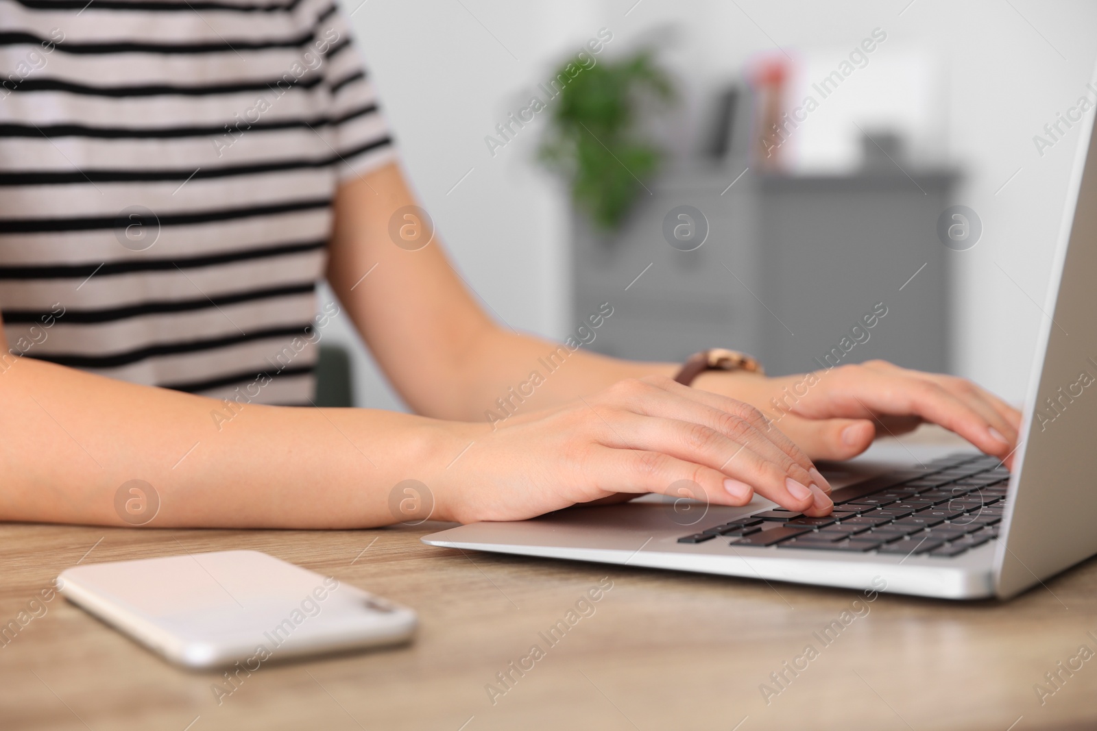 Photo of Woman working with laptop at wooden table indoors, closeup