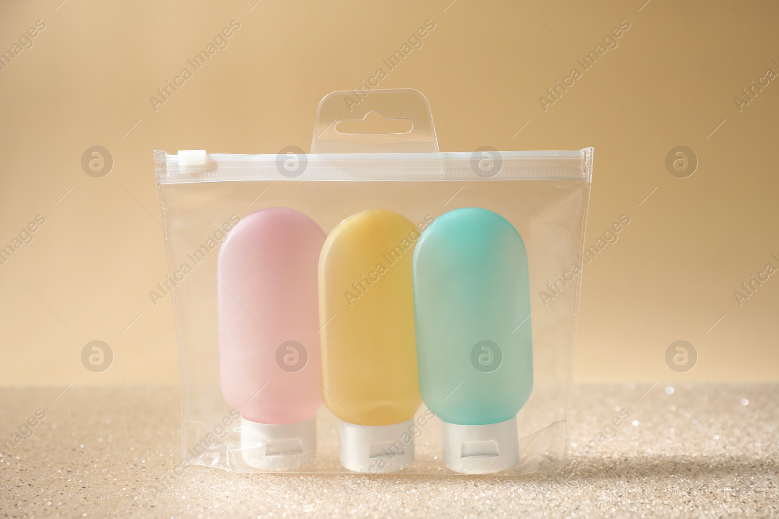 Photo of Cosmetic travel kit in plastic bag on beige background. Bath accessories