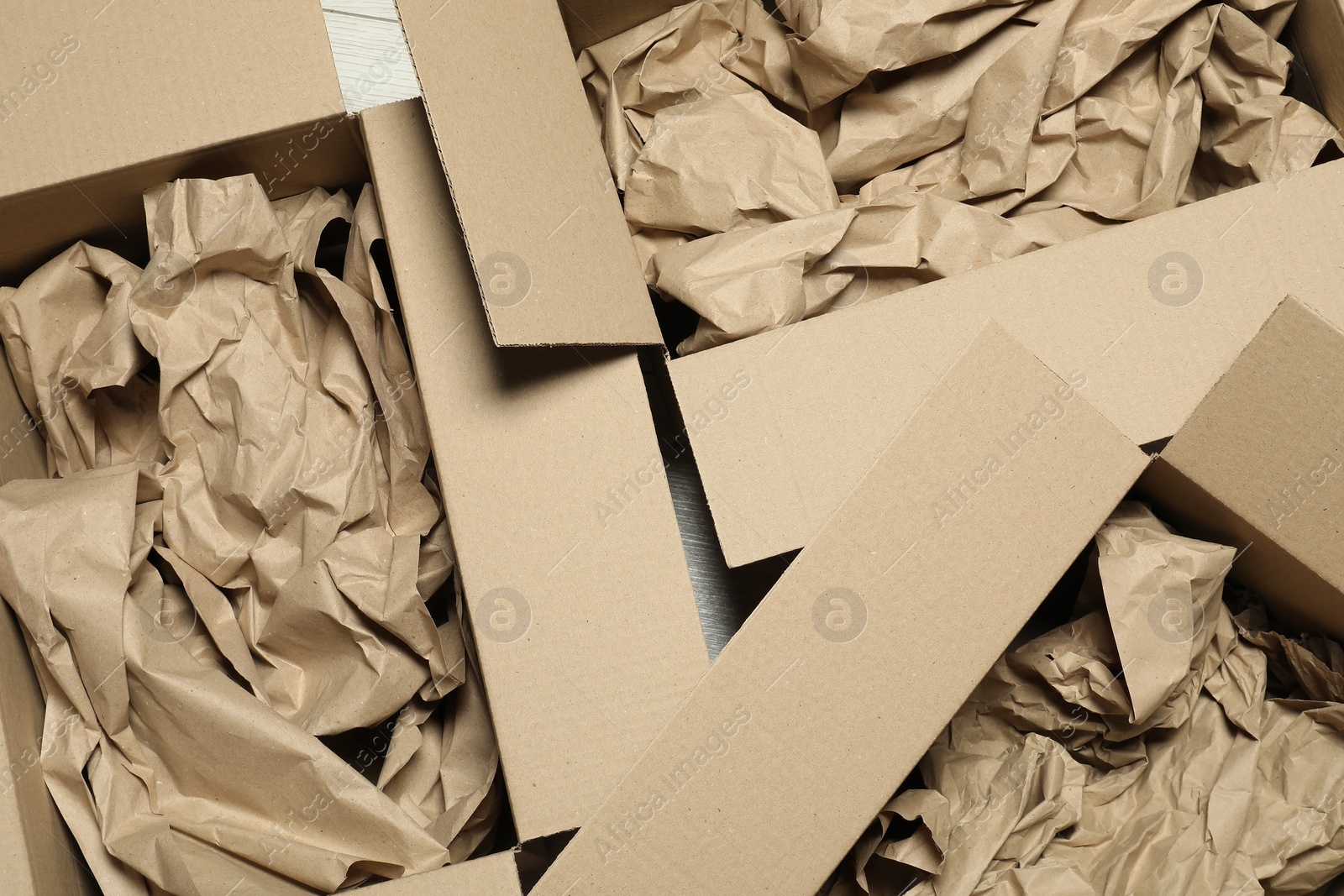 Photo of Open cardboard boxes with crumpled paper on white wooden floor, flat lay