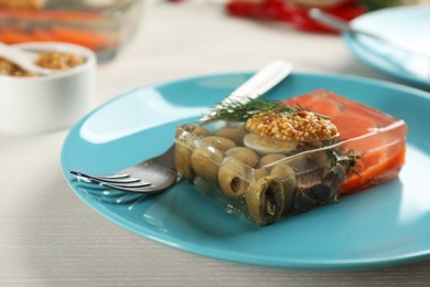 Photo of Plate with delicious aspic on white wooden table, closeup