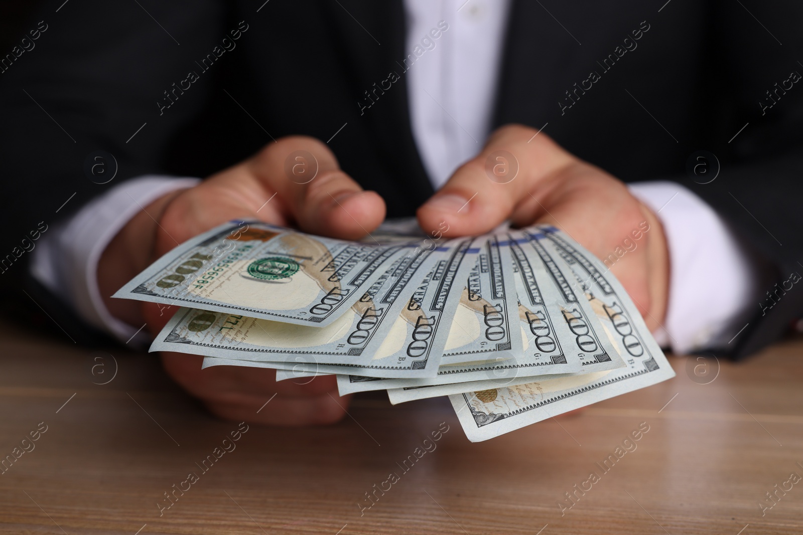 Photo of Money exchange. Man counting dollar banknotes at wooden table, closeup