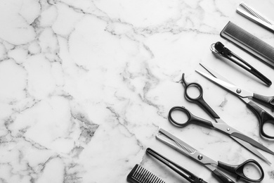 Photo of Flat lay composition with scissors and other hairdresser's accessories on white marble background. Space for text