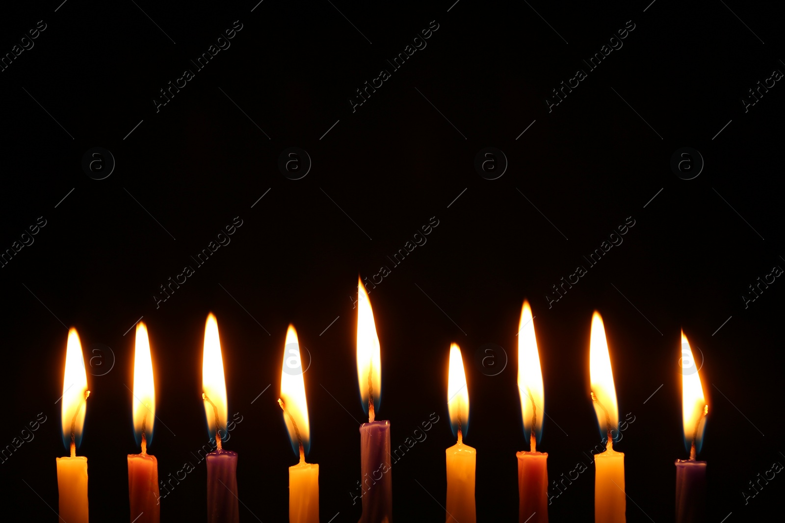 Photo of Hanukkah celebration. Burning candles on black background