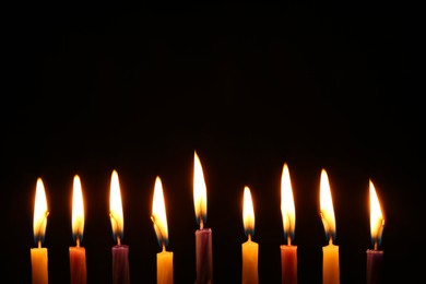 Hanukkah celebration. Burning candles on black background