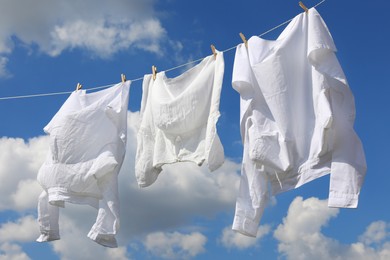 Photo of Clean clothes hanging on washing line against sky. Drying laundry