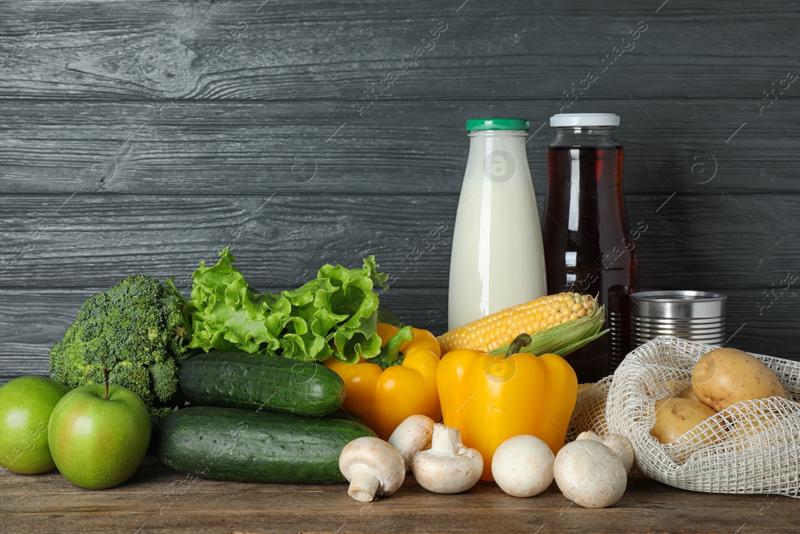 Photo of Different fresh vegetables and fruits on wooden table against dark background