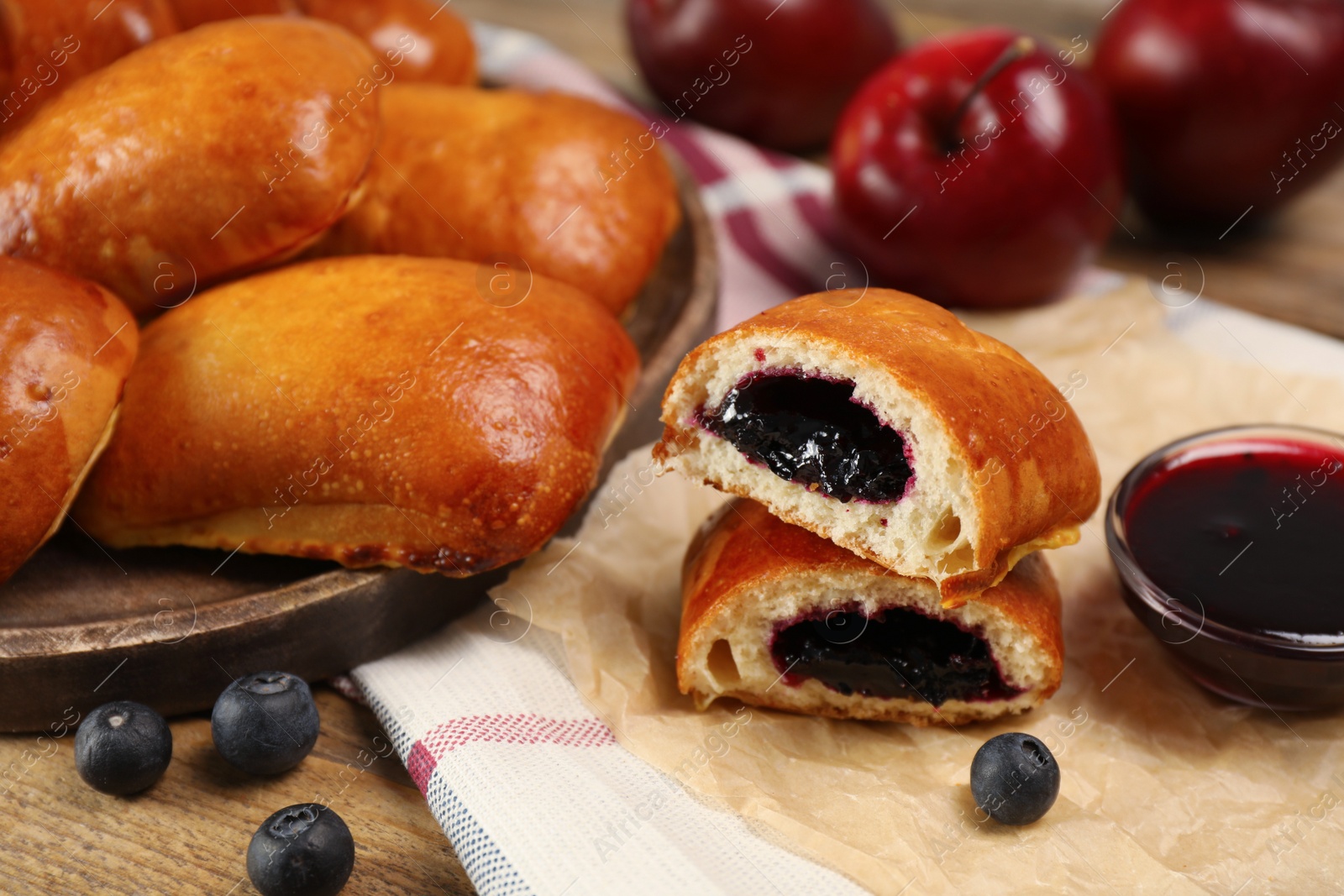 Photo of Delicious baked patties with jam and blueberries on table, closeup