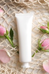 Tube of hand cream and roses in net bag on table, flat lay