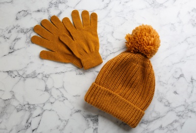 Photo of Stylish gloves and hat on white marble background, flat lay