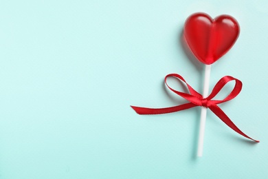 Photo of Sweet heart shaped lollipop on light blue background, top view with space for text. Valentine's day celebration