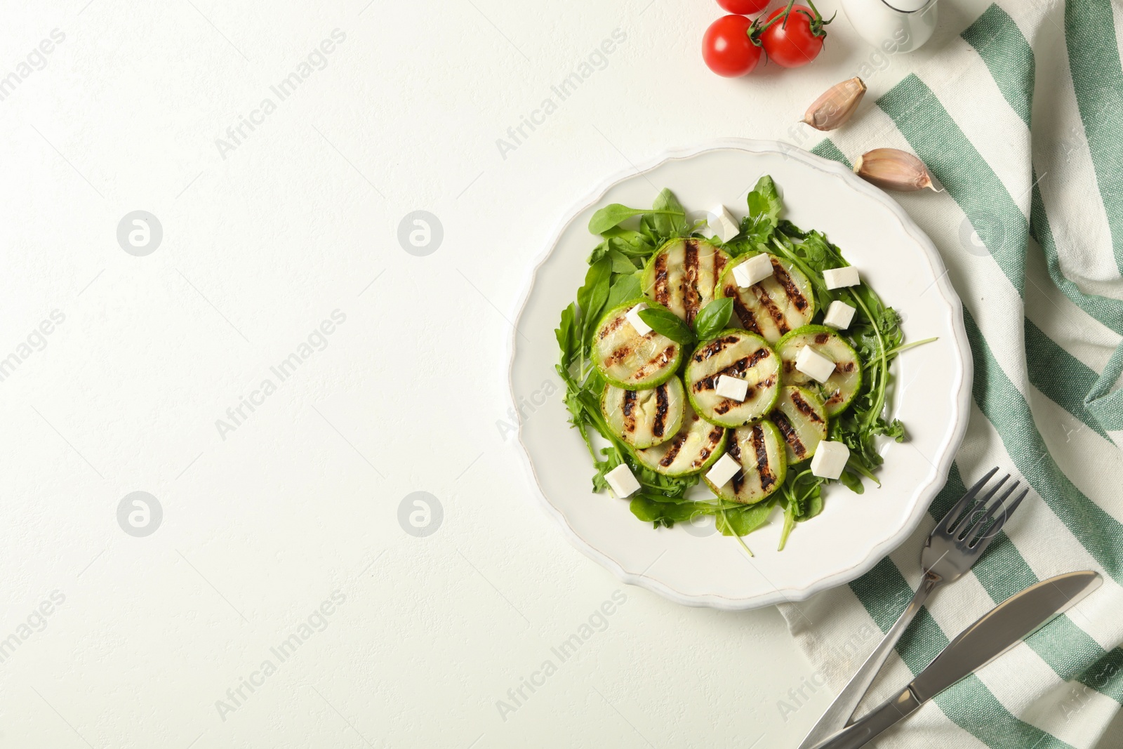 Photo of Delicious grilled zucchini slices and feta cheese on white table, flat lay. Space for text